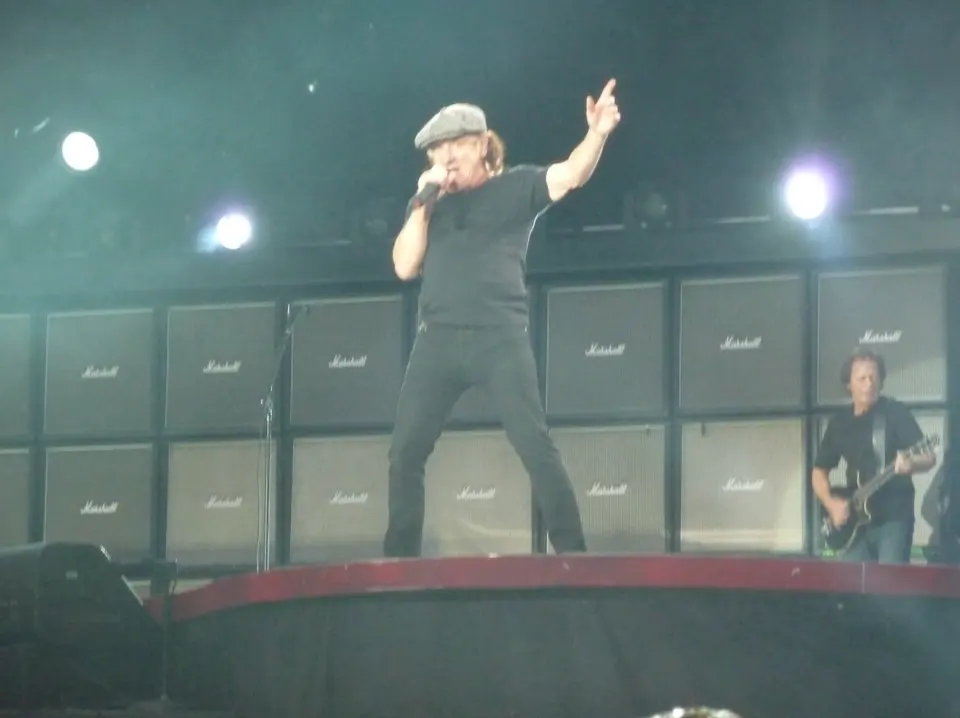 Brian Johnson, casquette vissée, bras levé