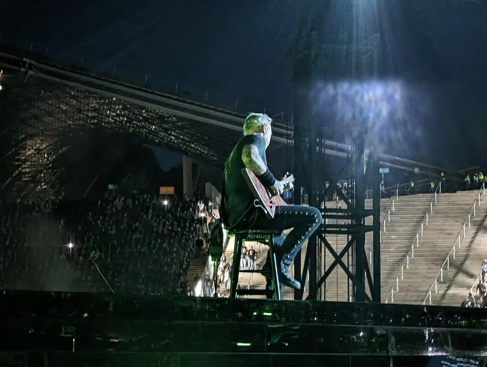 Hetfield assis, sous un faisceau